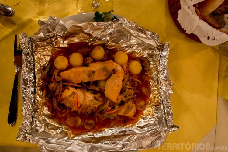 Prato servido com alimento enrolado em papel alumínio em mesa com toalha amarela