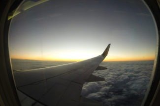 Crepúsculo acima das nuvens visto da janela do avião com asa no meio da imagem