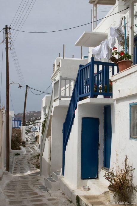 Casas brancas com portas, janelas e varandas de madeira em outra cor é o estilo arquitetônico em Myconos