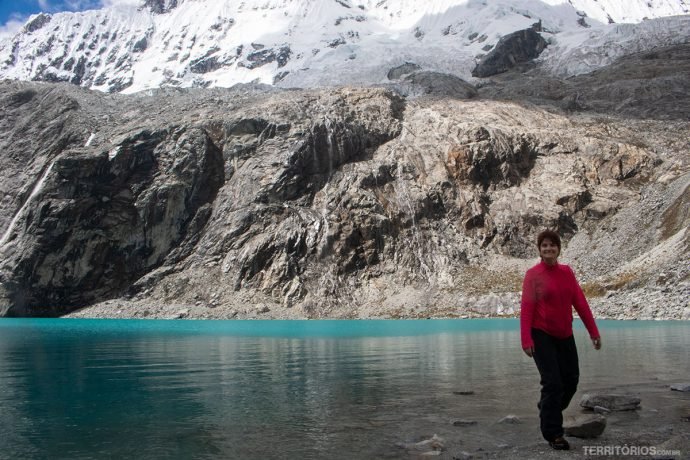Mulher em frente a lagoa de cor azul com montanha nevada ao fundo