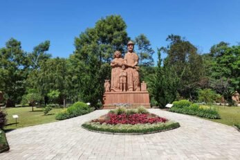 Escultura de um casal de imigrantes em cerâmica no meio de um jardim