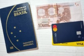 Euros em papel-moeda cada vez menos aceitos na Europa Passaporte brasileiro, nota de 10 euros e dois cartões de débito e crédito
