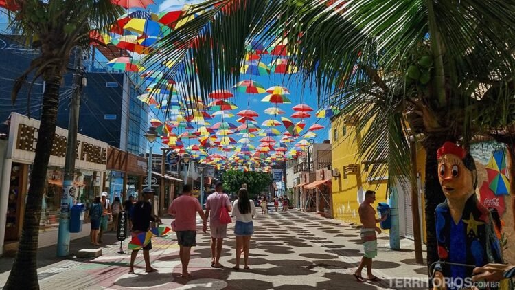 Calçadão de Porto de Galinhas com pessoas caminhando sob as sombras dos guarda chuvas coloridos