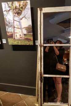 Reflexo de mulher no espelho ao lado de fotografia na parede do Hotel Swan Novo Hamburgo
