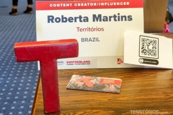 Letra T, cartões de visita e placa com nomes Roberta Martins e Territórios na mesa