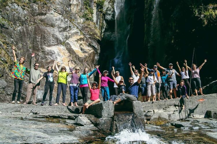 Grupo com roupas coloridas animado em frente a cachoeira