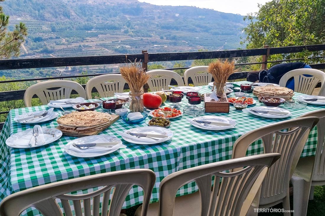 Mesa posta com culinária libanesa ao ar livre, vista para os vinhedos
