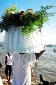Homem carrega oferendas com flores e panos para Iemanjá no dia 2 de fevereiro