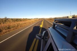 Alugar carro para viajar pelo Brasil Carro em movimento na estrada plana. Céu azul no horizonte.