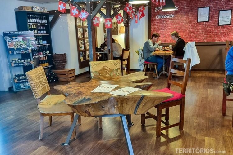 Interior de cafeteria com bandeiras da Suíça, mesa e cadeiras de madeira