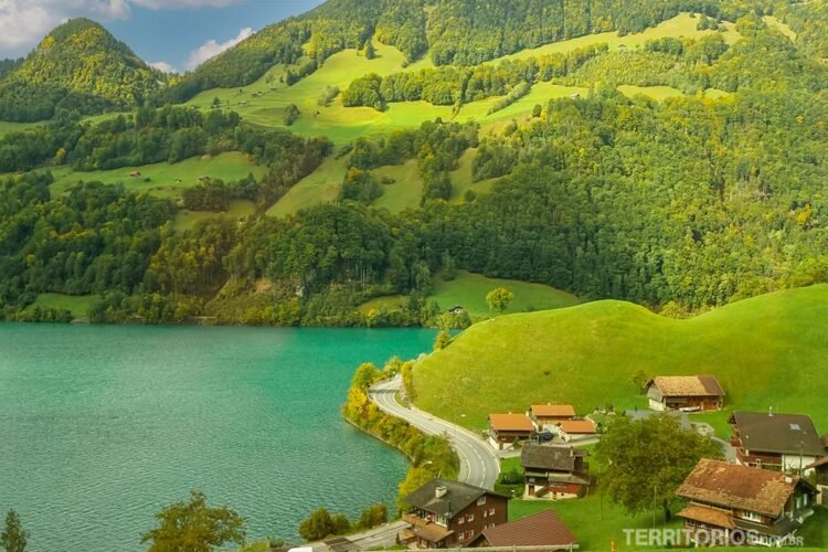Paisagem de Interlaken com lago e montanhas verdes, estrada e casas espalhadas