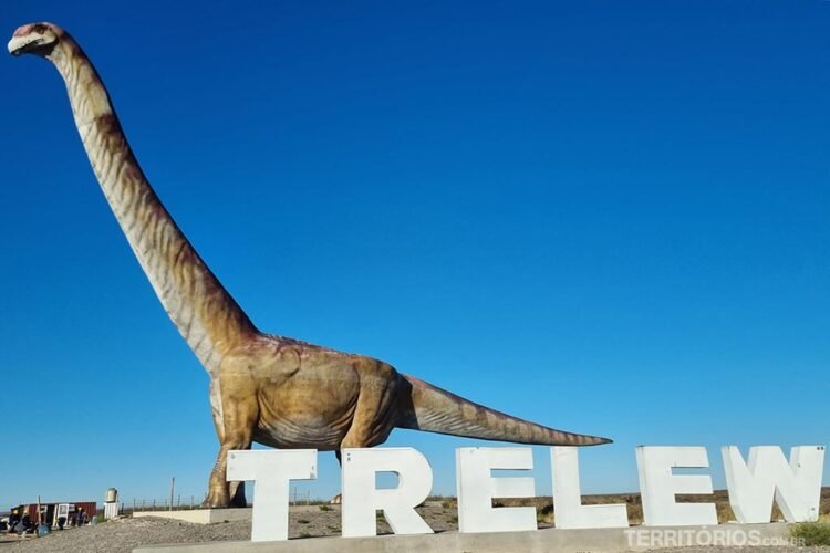 Réplica de dinossauro e letreiro de Trelew com céu azul