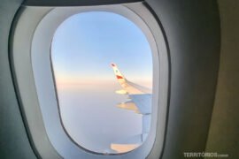 Buscadores de passagens x companhias aéreas x agentes de viagem Asa de avião vista da janelinha ilustra texto sobre buscadores de passagens aéreas