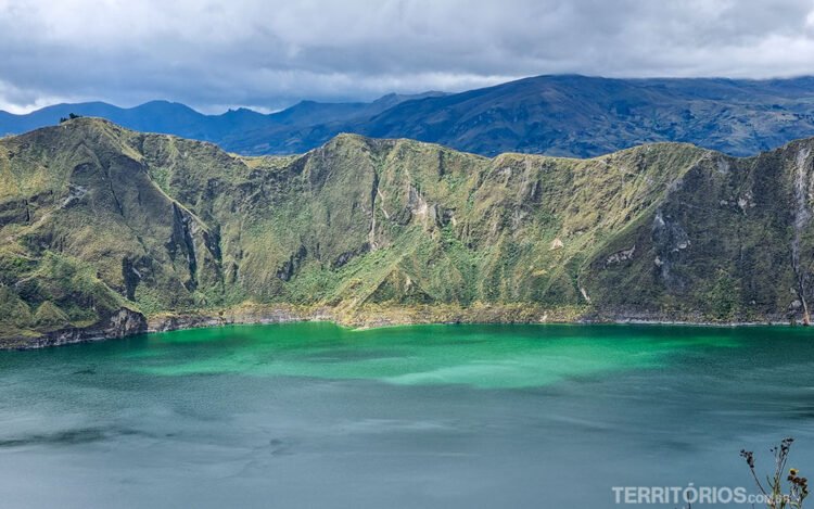 Lago cor de esmeralda e montanhas verdes em dia parcialmente nublado. Raio de luz no lago