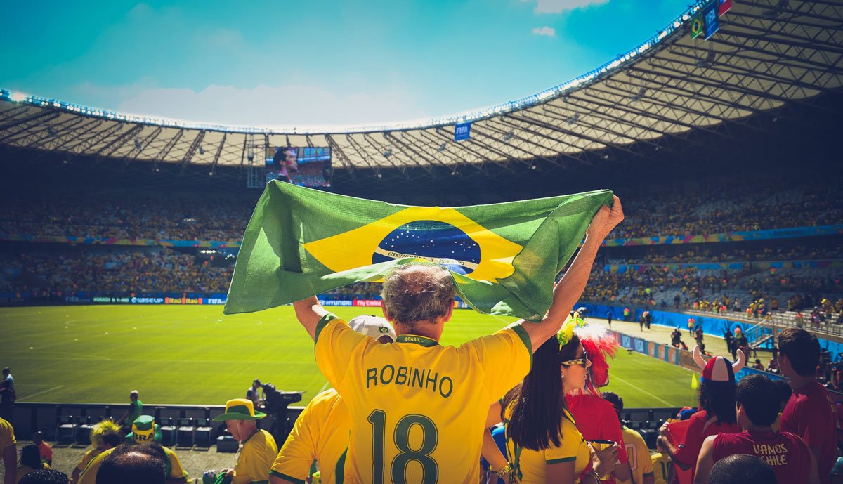 Torcedor de futebol e Brasil segura a bandeira em estádio de futebol.