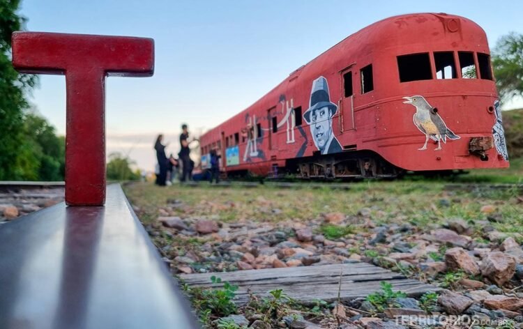Letra Tesão vermelha de madeira nos trilhos de uma ferrovia, locomotiva desativava ao fundo