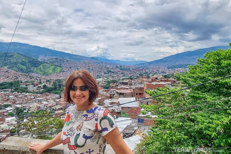 Mulher de óculos posa em mirante para vale onde fica parte de Medellín