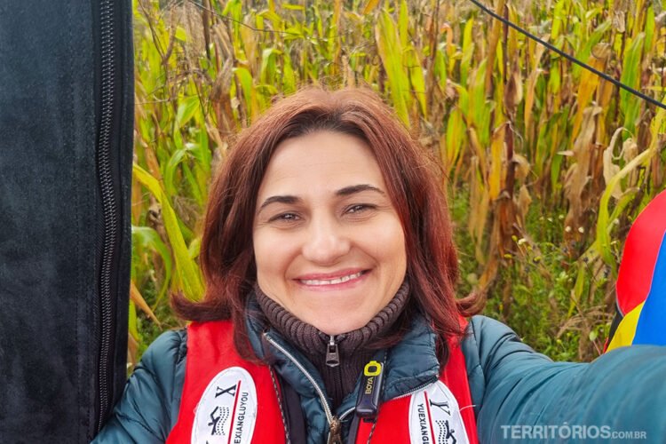 Mulher sorri fazendo selfie com milharal ao fundo. Zona rural de Otavalo