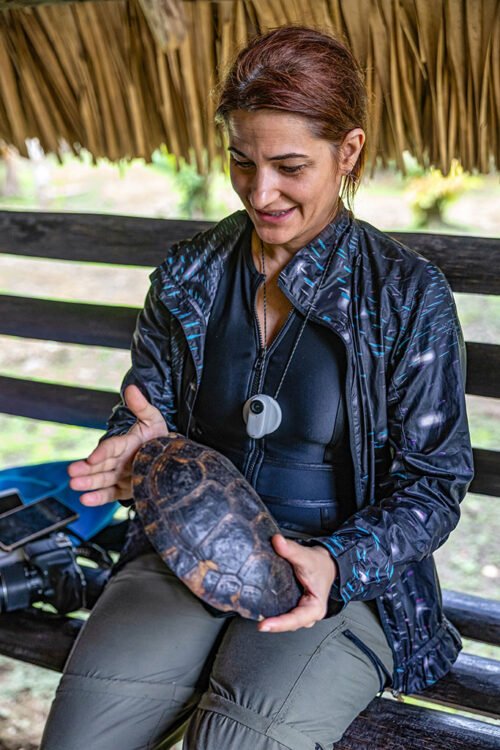 Mulher veste preto e olha para casco de tartaruga que serve como instrumento musical em Napo