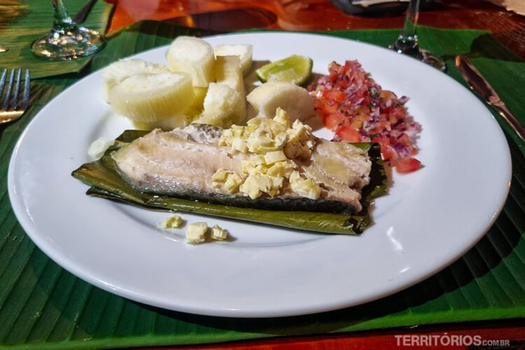 Prato servido com peixe e legumes sobre folha de bananeira no restaurante do Napo Cultural Center