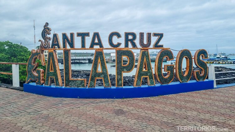 Letreiro escrito Santa Cruz, Galápagos na calçada em frente a marina 