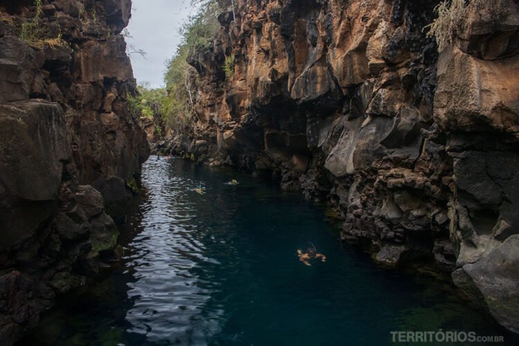 Las Grietas, cânion de pedras vulcânicas com água no interior. Pessoas nadam com snorkel em atrativo de Santa Cruz.