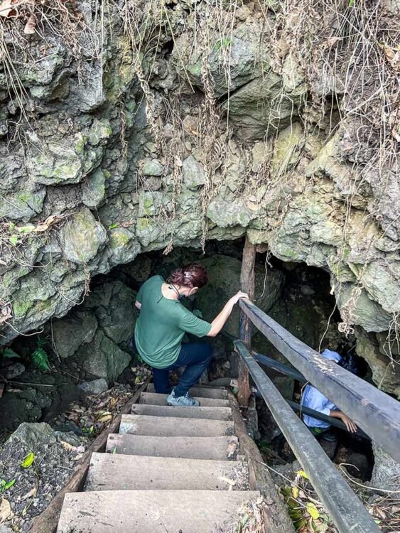 Mulher com blusa verde entra em túnel de lava na ilha Santa Cruz