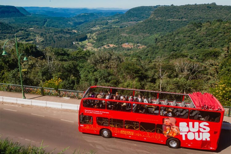 Ônibus de turismo vermelho na estrada com vista para vale verde