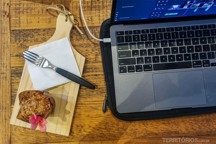 Computador sobre mesa com bolo, garfo, guardanapo e tábua ao lado