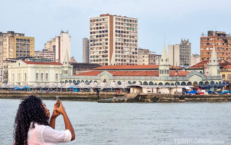 Mulher fotografa paisagem, rio e mercado na margem