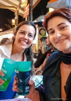 Duas mulheres brindam com copos de cerveja em bar no Novo Campeche