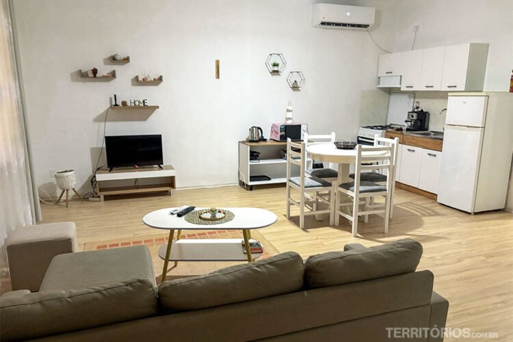 Sala de casa por temporada na Albânia. Sofá, TV, mesa, móveis de cozinha e ar-condicionado.