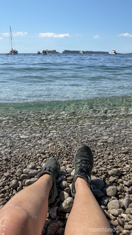 Pés de mulher molhados em frente ao mar com vista para barcos e ilhas da Baía de Kotor 