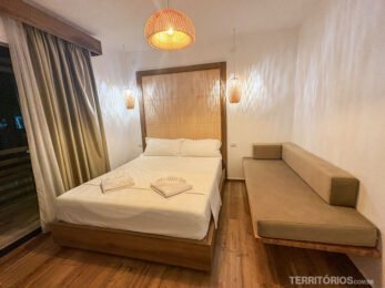 Quarto de hotel na Albânia com decoração rústica em tons bege, cama de casal e sofá