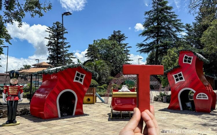 Letra T em frente a decoração de Natal na praça