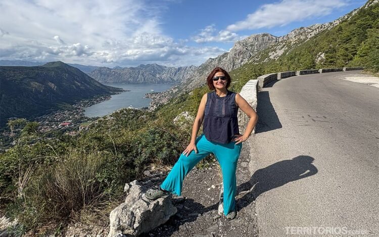 Mulher faz pose em mirante na beira da estrada com vista para a Baía de Kotor