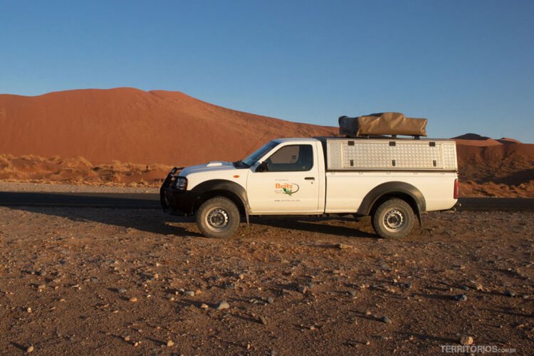 4x4 com barraca no topo em frente à duna vermelha durante roteiro pela Namíbia de carro